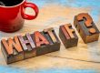 Red coffee mug beside vintage wooden letter blocks spelling 'NEW YEAR' on a distressed blue wooden surface.