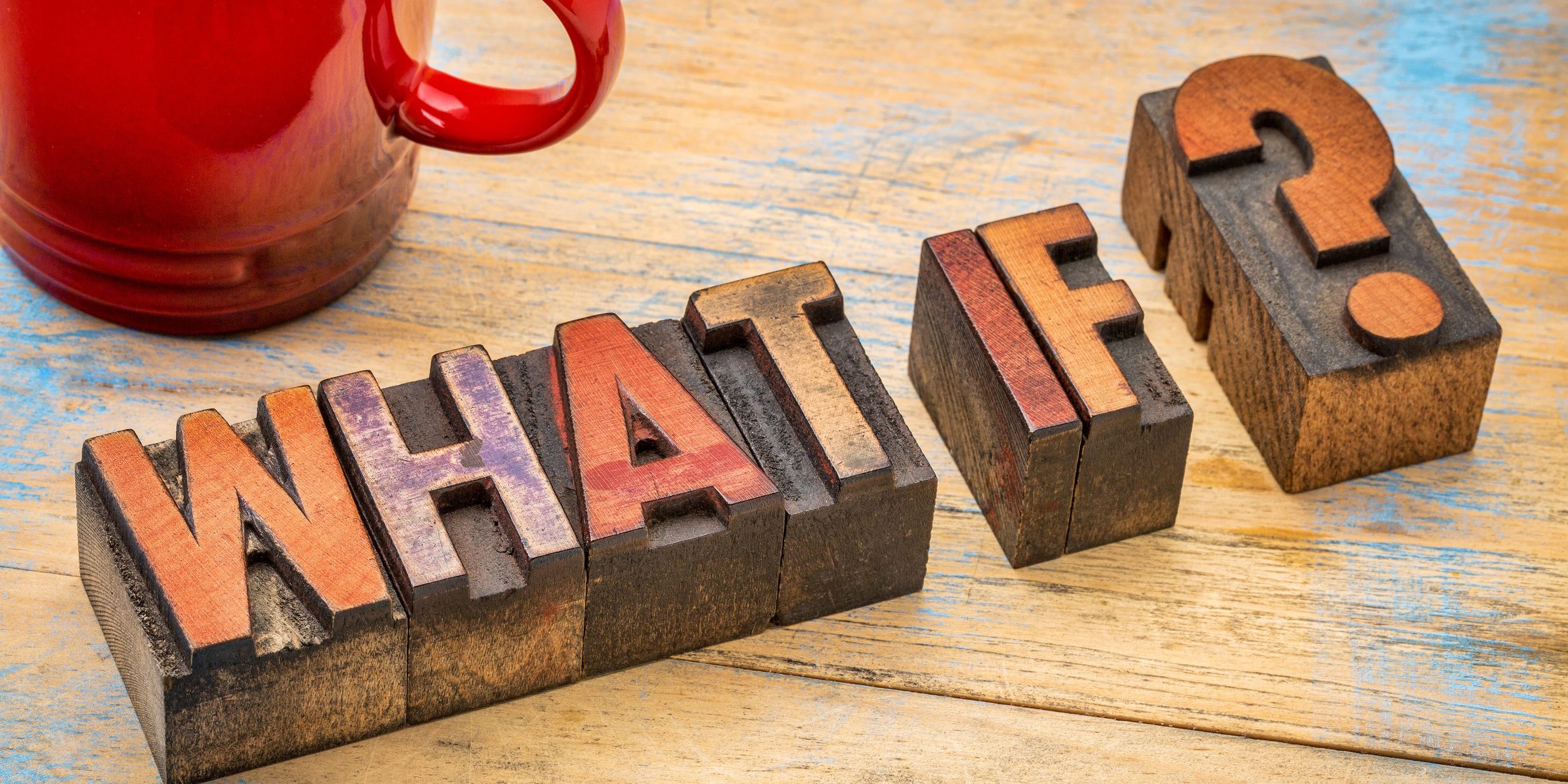 Red coffee mug beside vintage wooden letter blocks spelling 'NEW YEAR' on a distressed blue wooden surface.